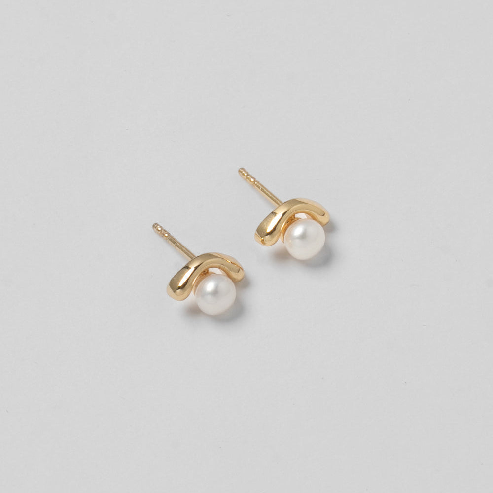 Gold earrings with pearl studs on a light gray background