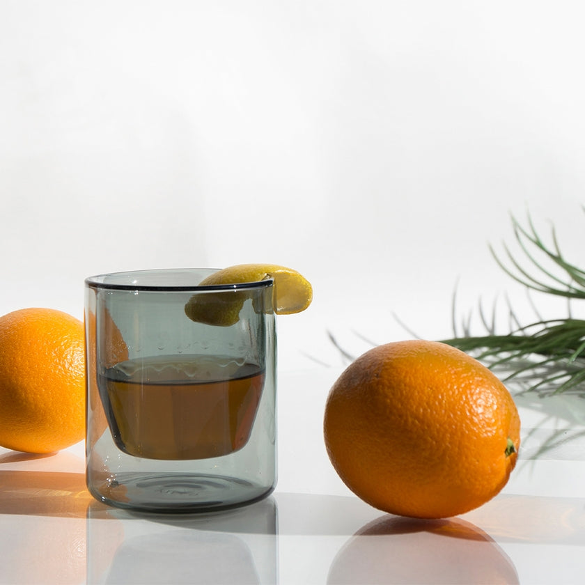 Clear glass with lemon and orange on a white surface