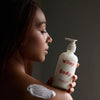 Woman applying Wiley Body lotion to her shoulder against a dark background