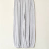 Gray sweatpants hanging on a wooden hanger against a white wall