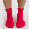 Red socks with ruffled top worn by a person on a white background by Baggu