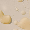 Close-up of body oil liquid droplets on a light beige background
