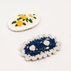 Two embroidered crochet hair clips on a white background