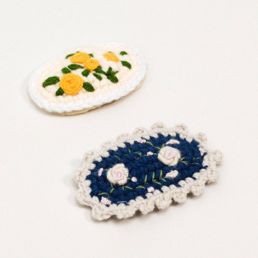 Two embroidered crochet hair clips on a white background