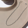 Silver chain necklace on a beige surface