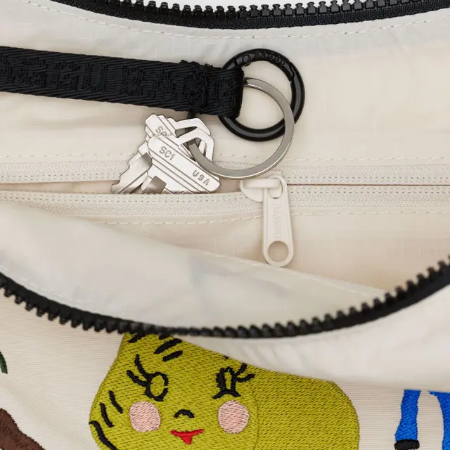 Close-up of a pouch with a zipper, keychain, and embroidered design.