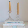 Two vintage crystal candlesticks sitting atop a stack of books.