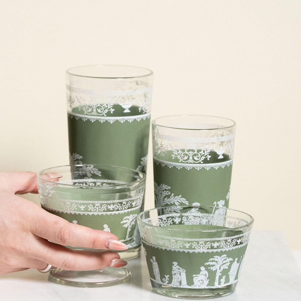 Set of green glass tumblers with white patterns on a light background