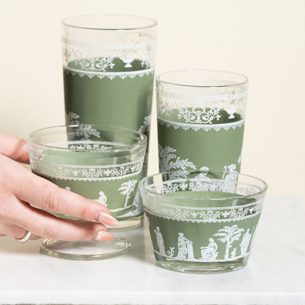 Set of green glass tumblers with white patterns on a light background