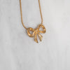 Gold bow-shaped pendant necklace on a light gray background