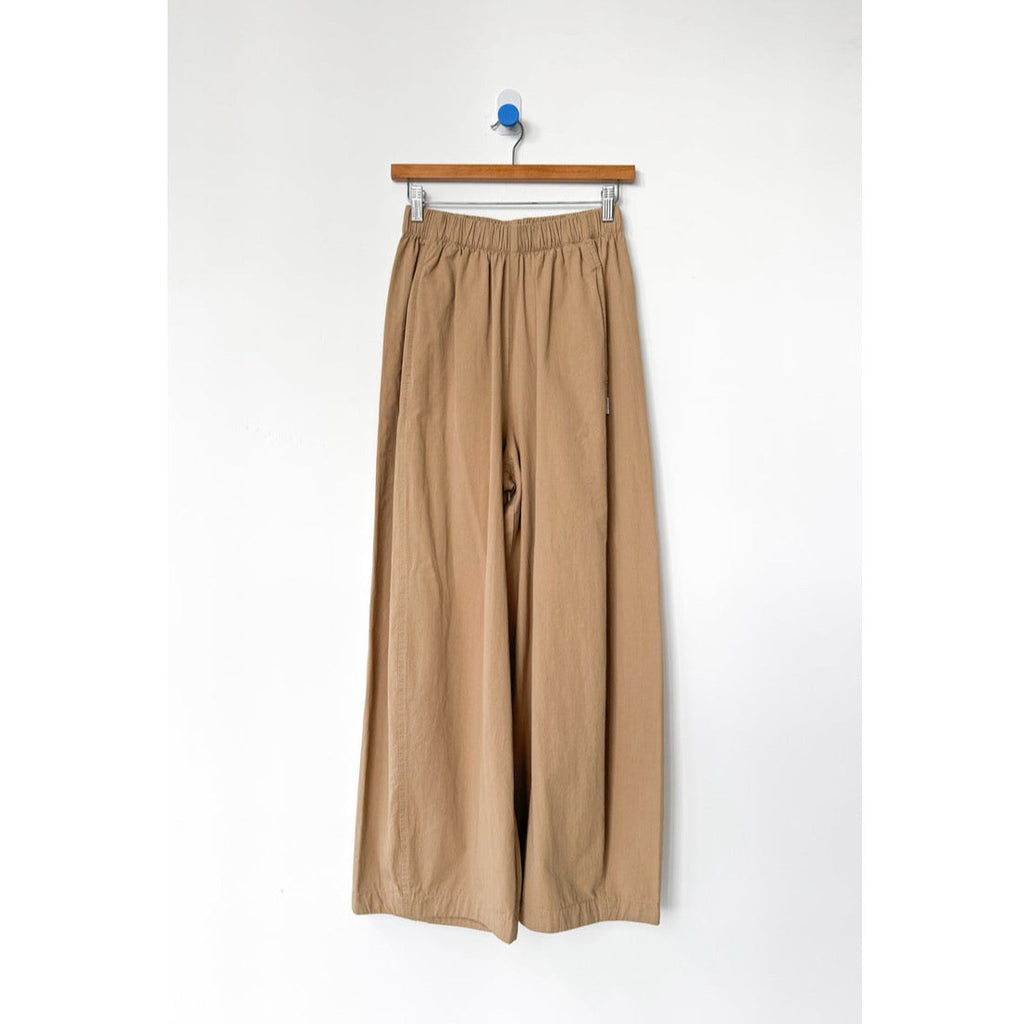 Beige wide-leg pants hanging on a white background