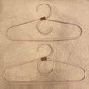 Two pink hangers with brown hooks on a textured beige background