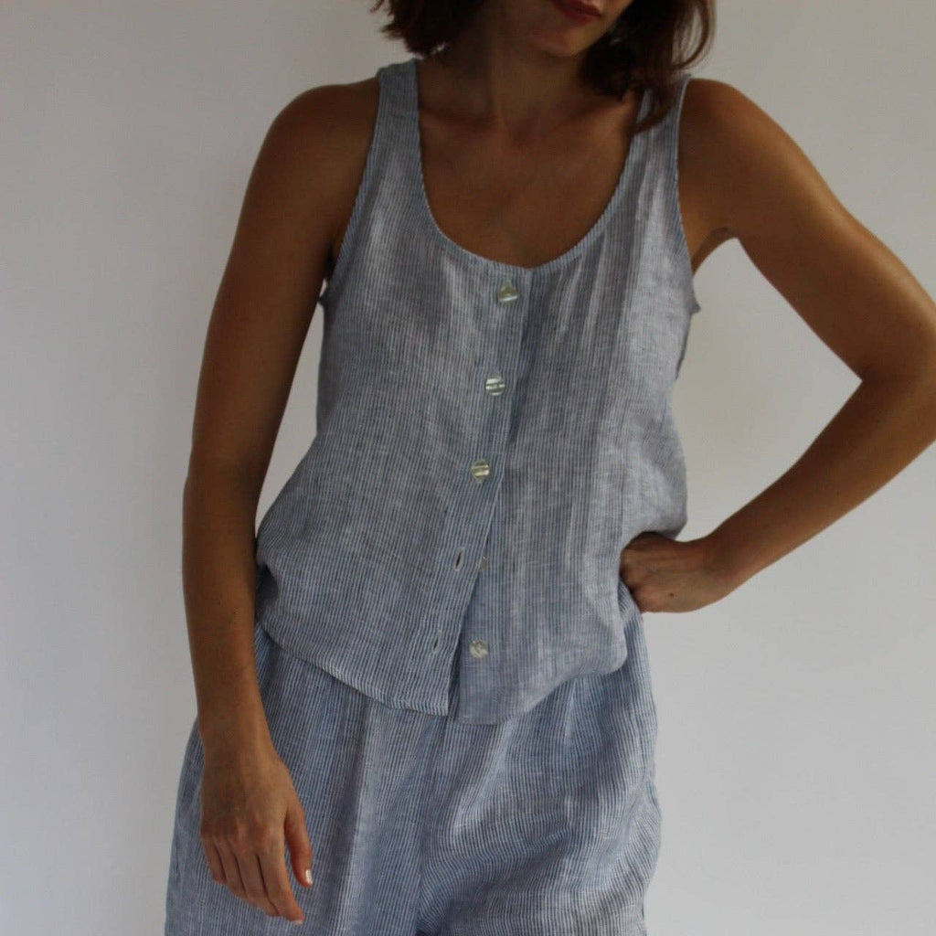 Person wearing a light blue sleeveless top and pants set against a plain background