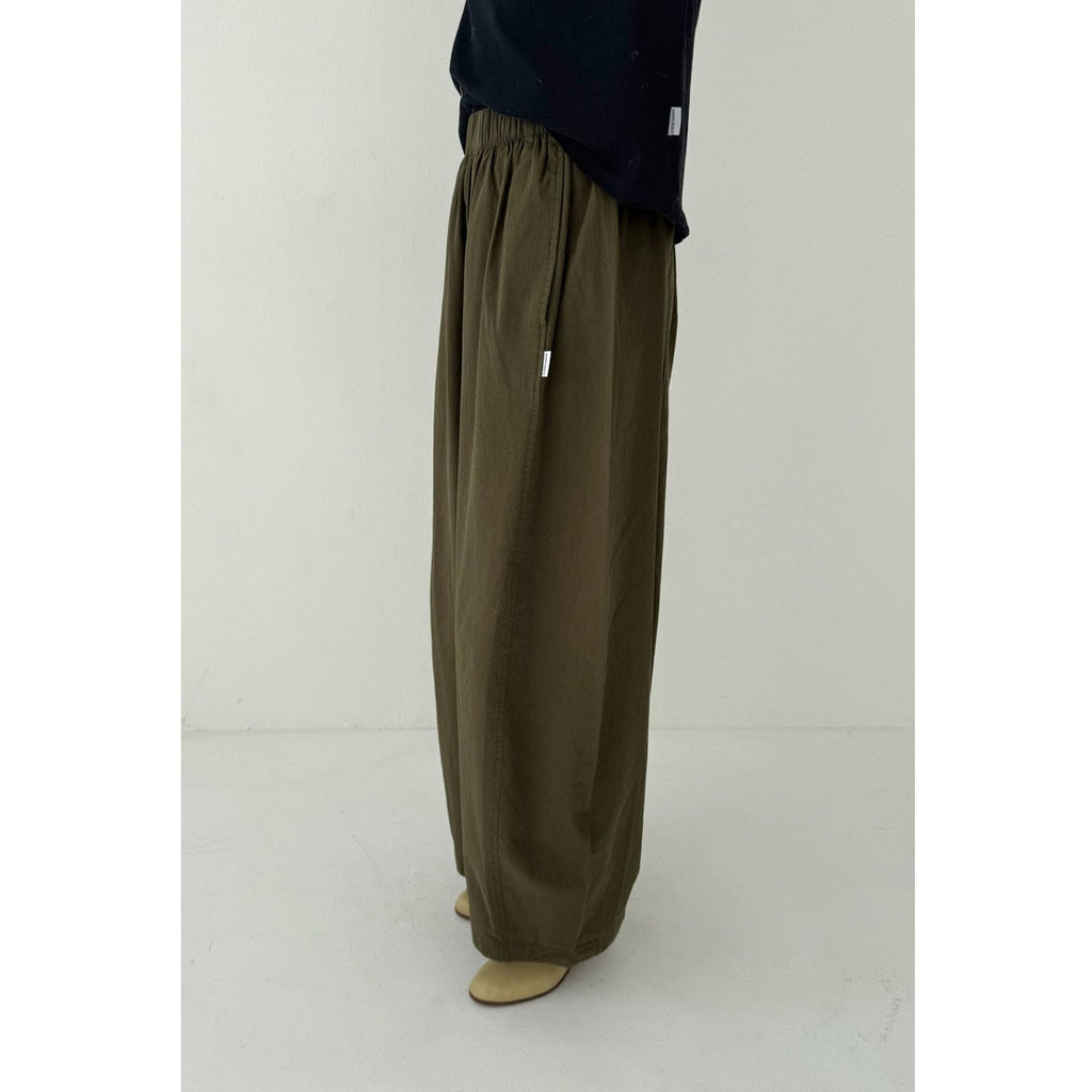 Person wearing olive green wide-leg pants on a white background
