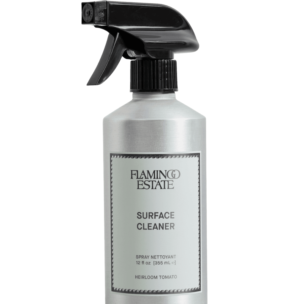 A 12 fl oz silver spray bottle of Flaming Estate Surface Cleaner with a black trigger spray top and a white label, isolated on a white background.