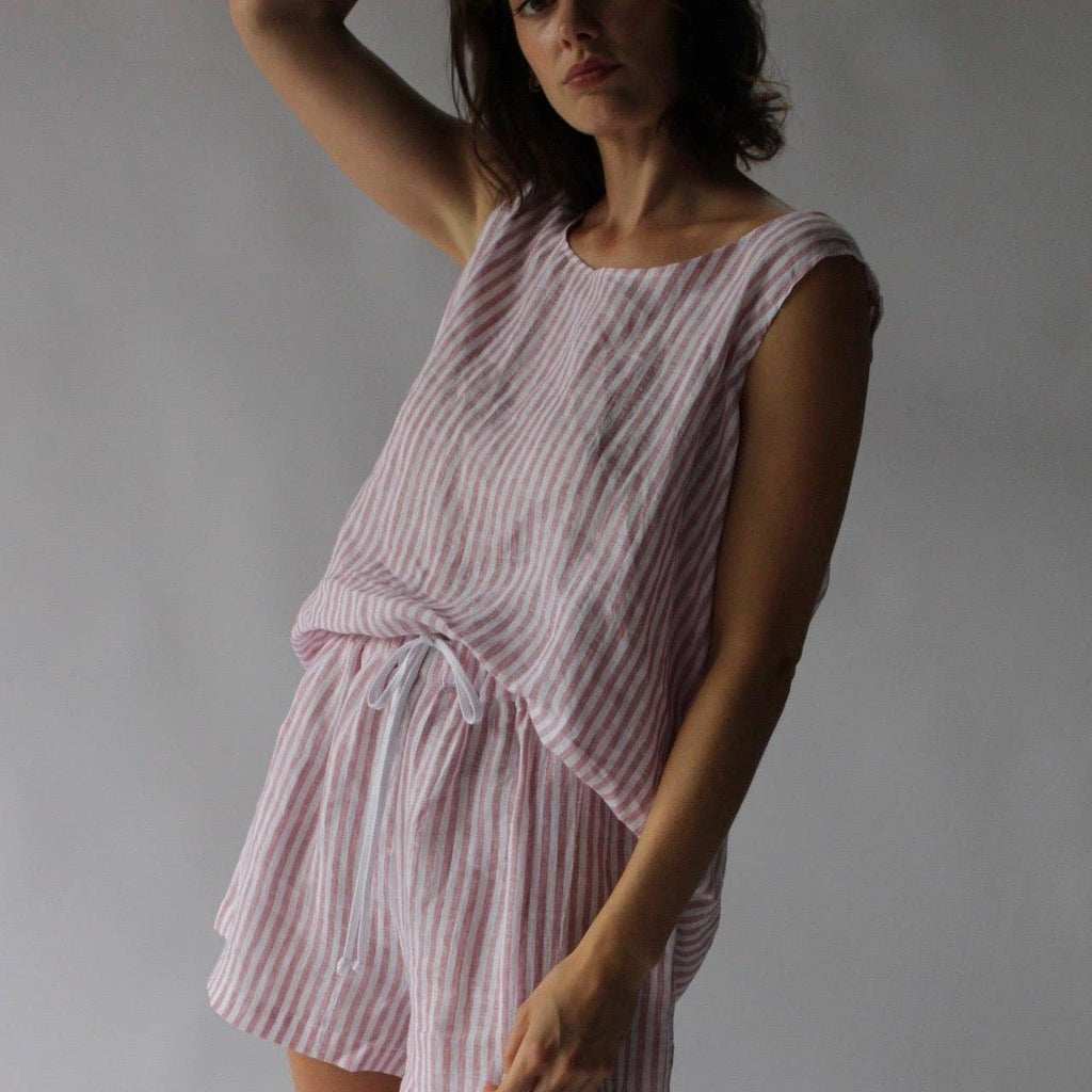 Woman wearing a pink and white striped linen shirt against a plain background