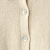 Close-up of a beige cardigan with shell buttons on a beige background