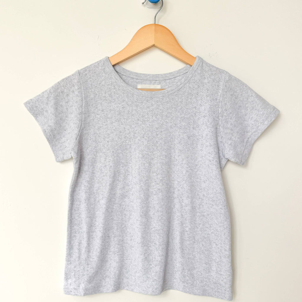 Gray t-shirt on a wooden hanger against a beige background