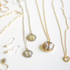A collection of Sanibel Coquina Shells set in resin in gold and silver pendants.