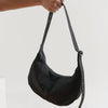 Model Holding Up Black Baggy Nylon Crescent Bag with Adjustable Strap