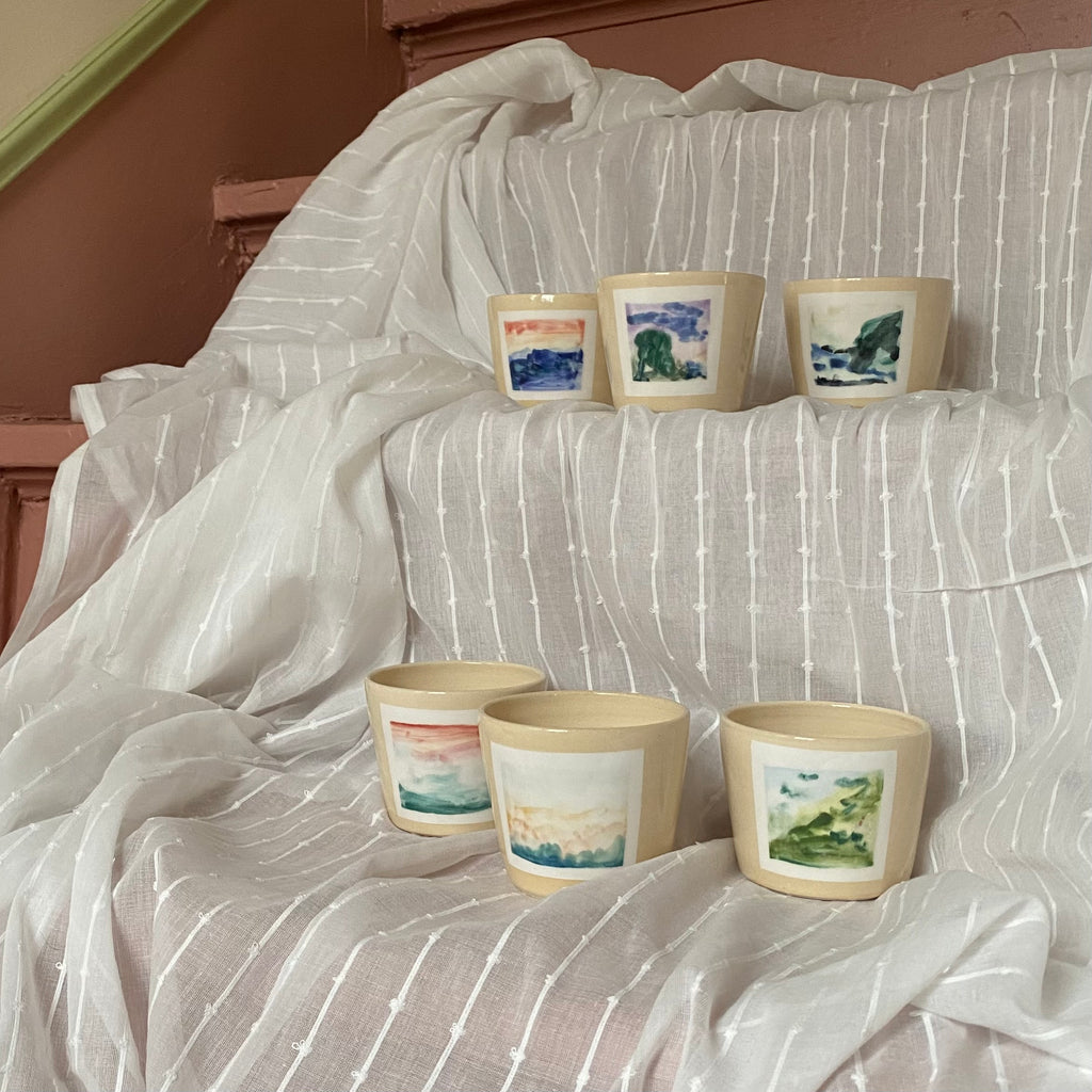 Hand Painted Landscape Ceramic Cups on a White Fabric on Pink Stairs